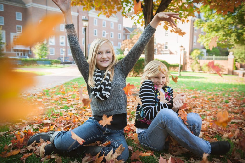 sisters play in leaves in uptown athens ohio near court stree