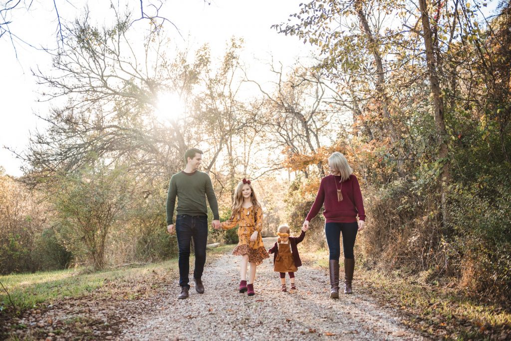 family wearing fall cothes to photoshoot with sun shining behind them