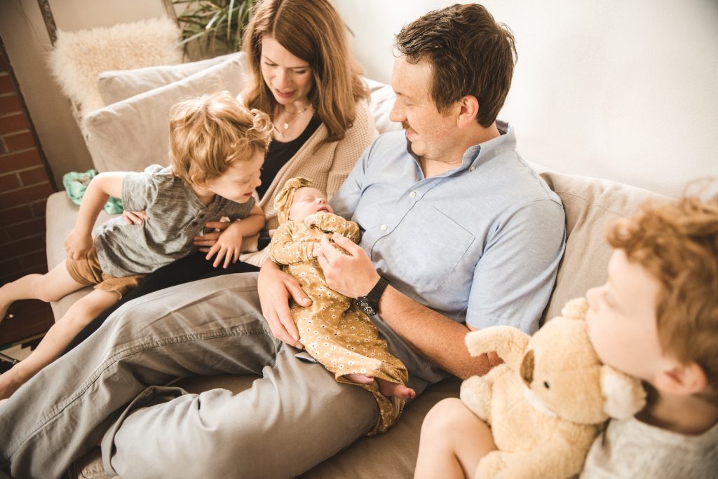 family sitting together on couch with newborn