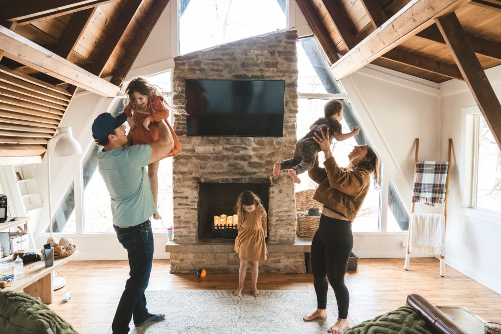 family dancing in their living room with lots of window and natural light