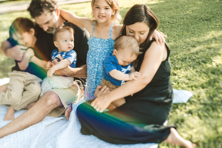 Parents sitting close with their children on a blanket, showing relaxed and connected poses for family photos.
