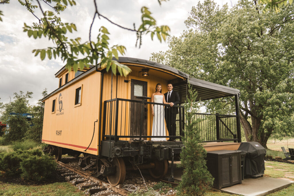 Bride and groom standing on yellow train car at Hideaway on the hocking in Athens ohio