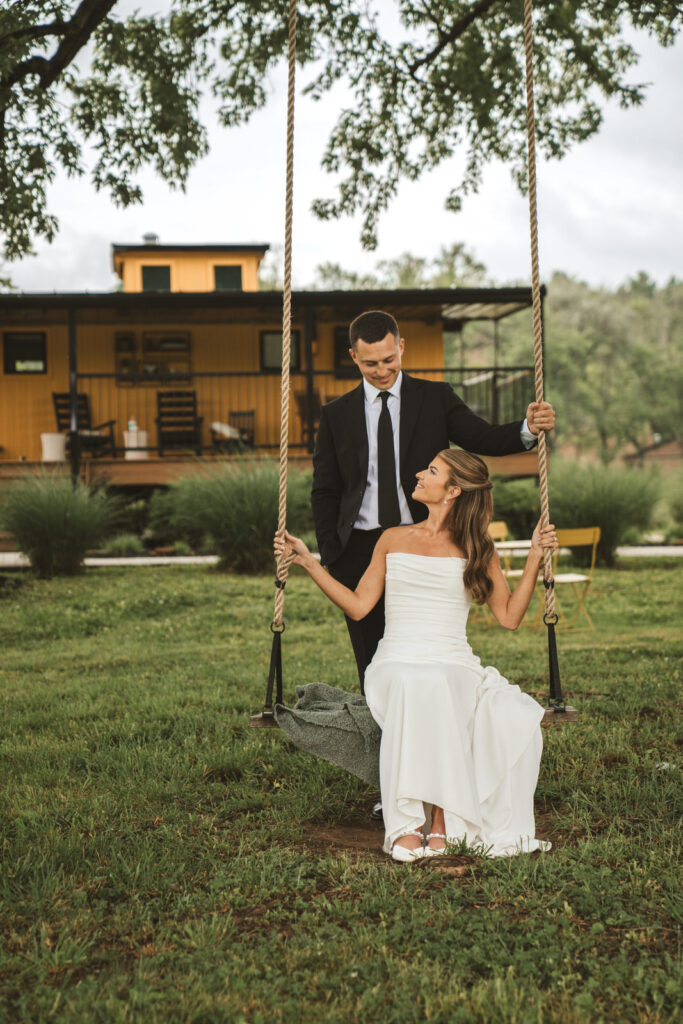 bride sitting on swing outside train caboose in Athens ohio at wedding venue Hideaway on the Hocking